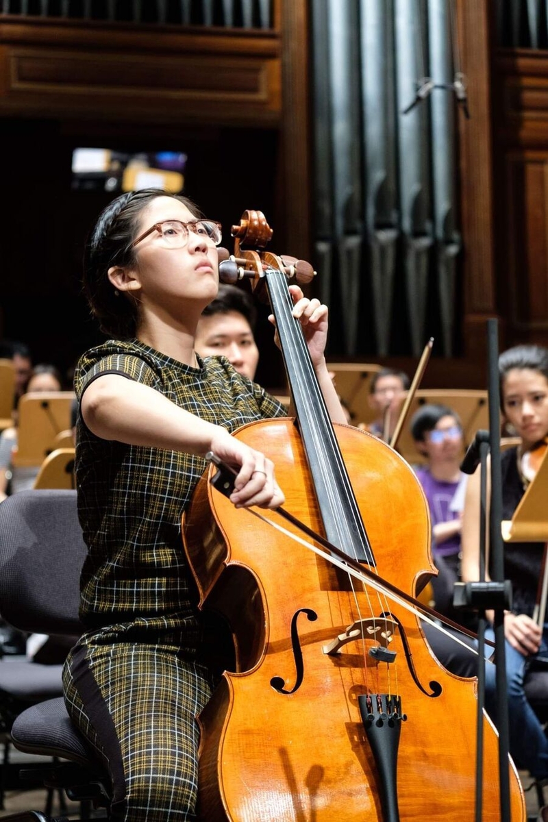 Melissa Ong with playing cello with an orchestra