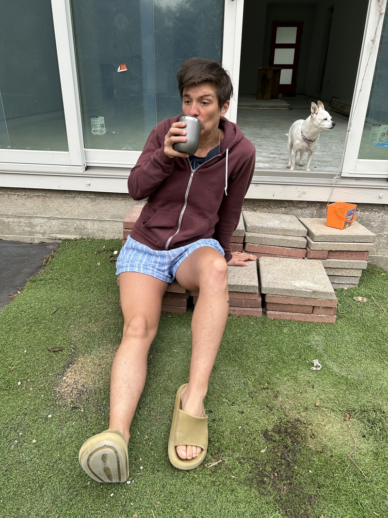 Sarah Wylie drinking coffee with a small dog. The dog is not drinking coffee