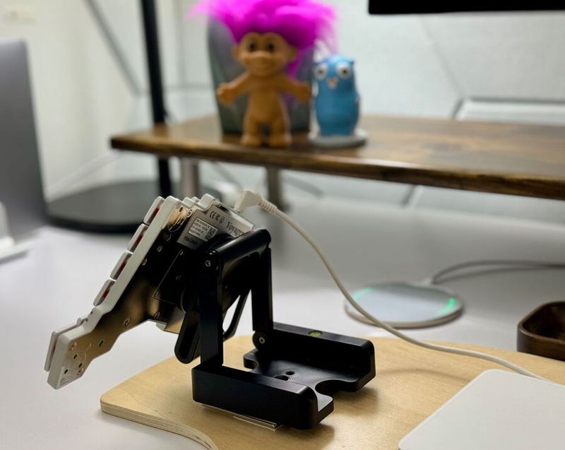 alt="Half of a split keyboard on a Z-shaped camera mount. The back of the keyboard faces the camera, and the keyboard is steeply tented and rotated so that it's at about a -25 degree angle relative to a line parallel to the table."
